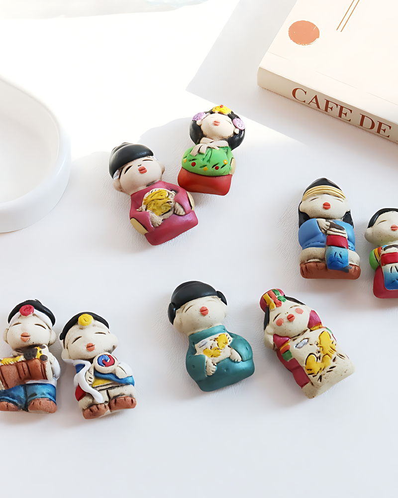 "meta_description": "Traditional ceramic magnet depicting couples in traditional attire. Add cultural charm to your home.",