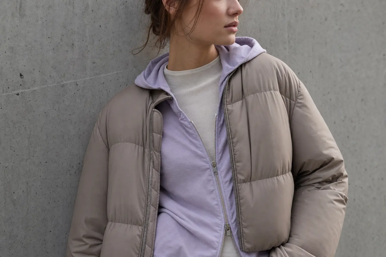 A close-up on layered textures: a slim merino base peeking from under a thin hoodie, topped by a matte nylon cropped puf