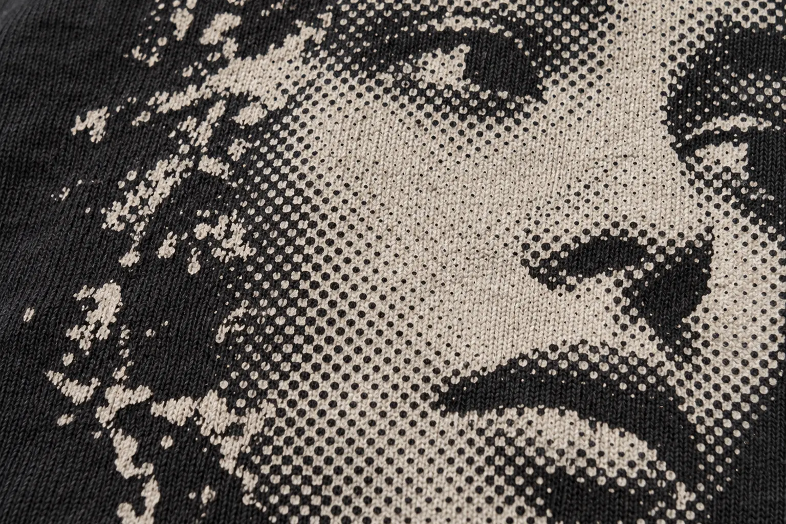 A macro photograph of a screen-printed halftone portrait on cotton jersey, showing dots of varying size forming a face,